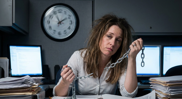 Женщина в офисе выглядит измотанной, вокруг неё вращаются часы, символизирующие выгорание и бесконечные задачи. Она держит разорванную цепь, что означает разрыв порочного круга.