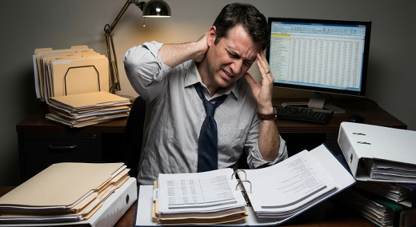 Мужчина в офисе испытывает боль в шее и плечах из-за стресса от работы, что символизирует психосоматическую связь между эмоциональным напряжением и физическим дискомфортом.