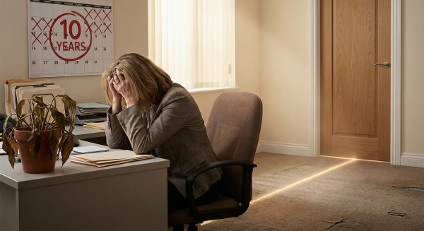 Женщина средних лет в офисе, испытывающая эмоциональное истощение и размышляющая о переменах, с символами выгорания и возможного нового пути.